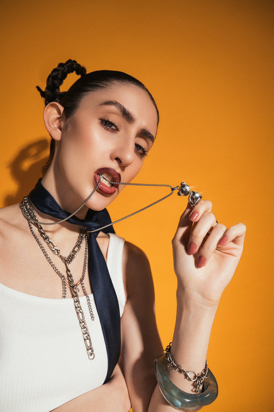 A woman poses with jewelry against a bold background.