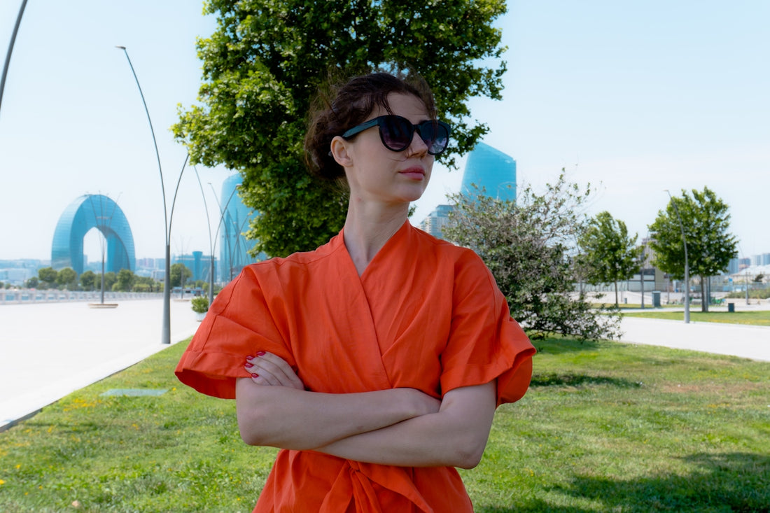 Woman in orange dress with arms crossed outdoors