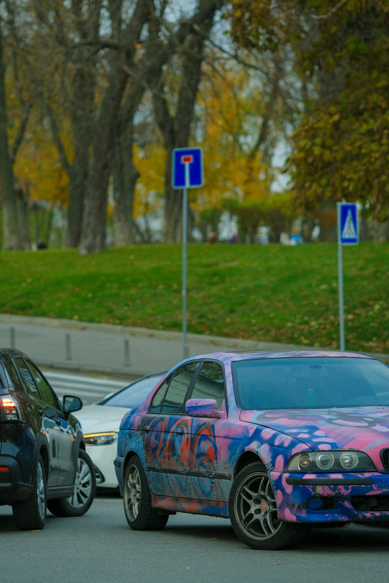 Cars with graffiti in traffic on a street.