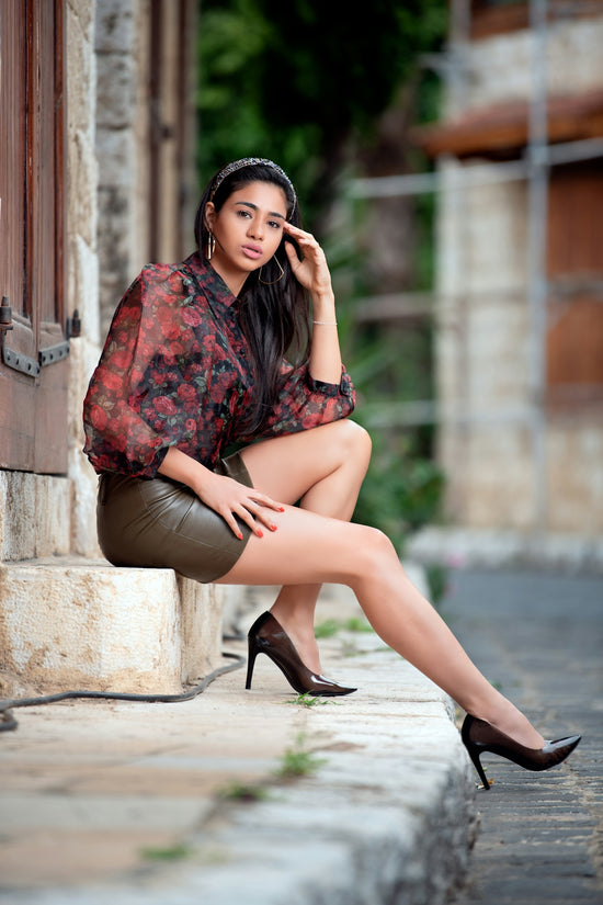 Young woman in stylish outfit sitting on stone steps.