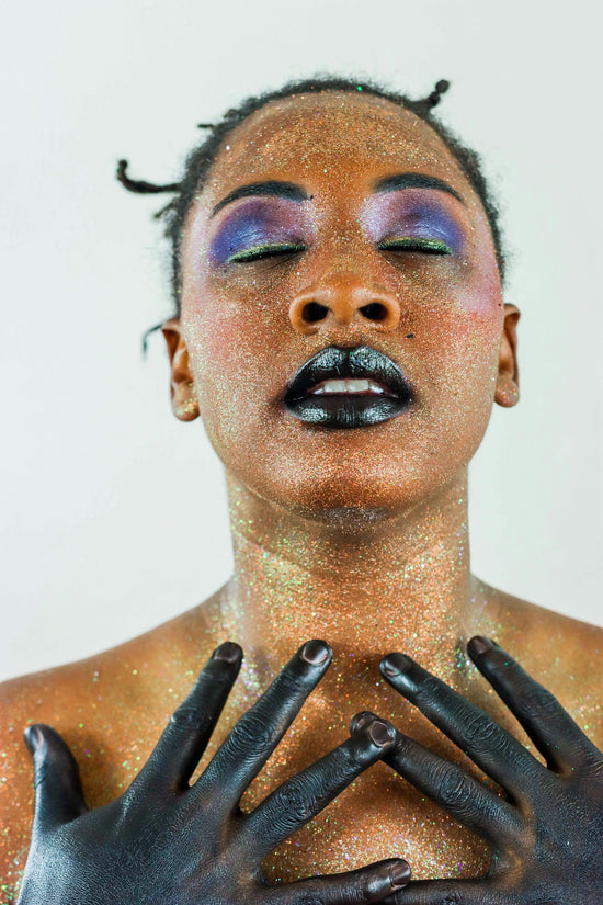 Woman with glitter makeup and black painted hands