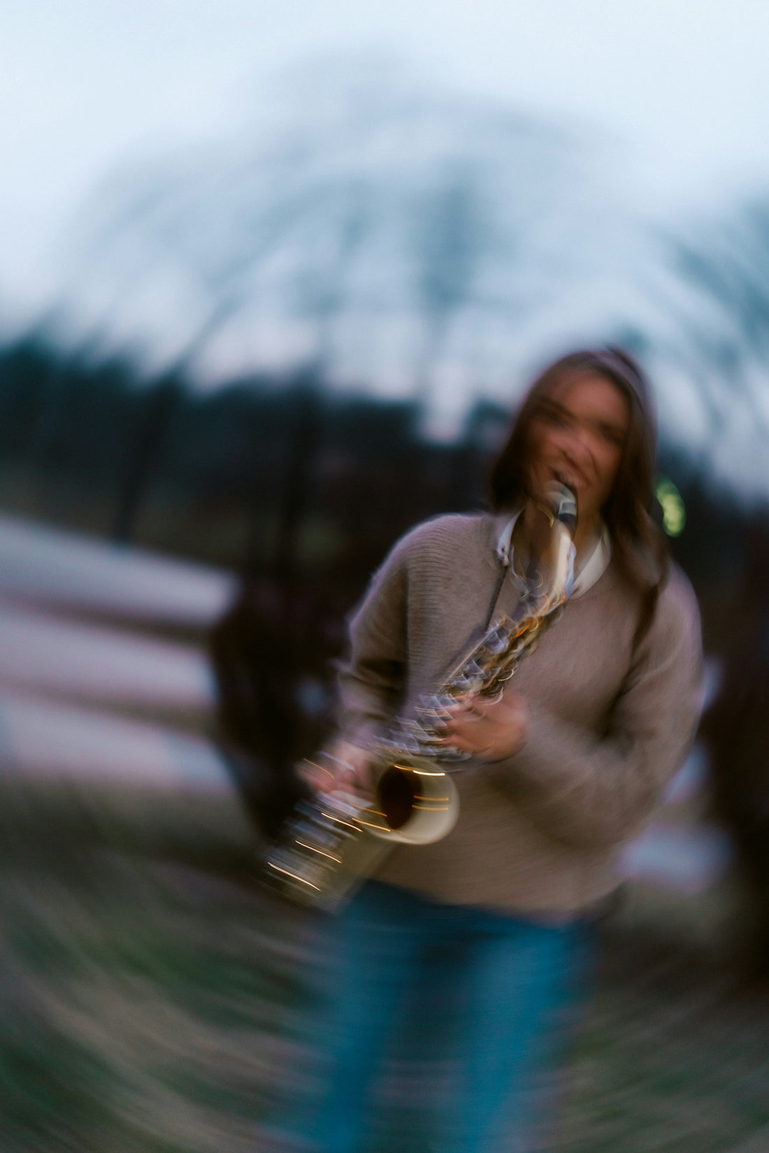 Woman playing saxophone outdoors with blurred background