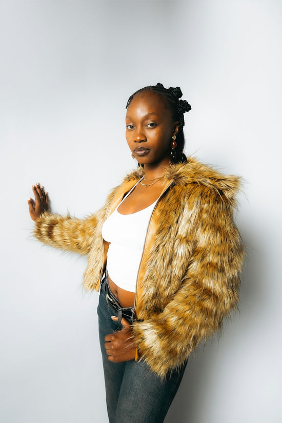 Young woman in a furry jacket and jeans poses.
