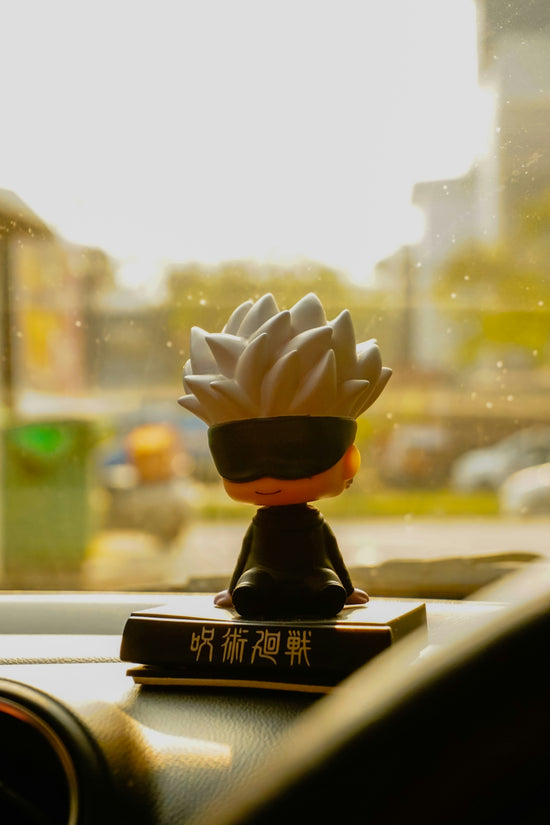 A figurine with a blindfold sits on a dashboard.