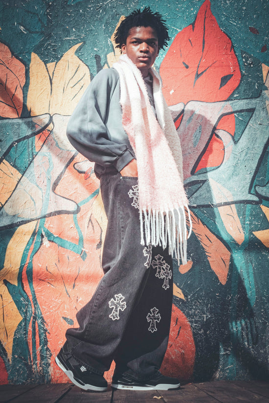Young man posing against graffiti wall wearing baggy jeans.